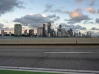 an empty freeway with city in the distance during sunset time against a blue cloudy sky