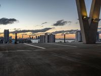 the sun sets behind a large building near the ocean with lots of tall buildings in front