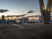 the sun sets behind a large building near the ocean with lots of tall buildings in front