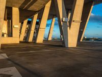 a building has some tall cement pillars in it and there is light shining from the top