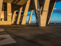 a building has some tall cement pillars in it and there is light shining from the top