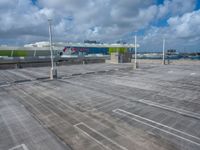 a parking lot is shown with a bus in the background as clouds gather overhead and there are several airport gates