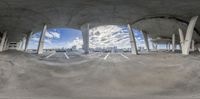 a view of buildings from a fish eye lense in the center of a parking garage