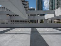 a white cement parking lot with skyscrapers in the background against a blue sky overhead