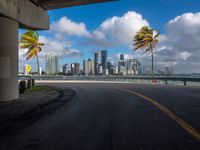 a deserted road with tall buildings in the distance by the sea side in miami, florida