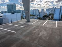 an empty parking lot is pictured against the sky with clouds in the background from a building