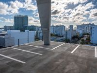 an empty parking lot is pictured against the sky with clouds in the background from a building