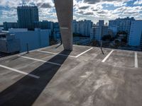 an empty parking lot is pictured against the sky with clouds in the background from a building