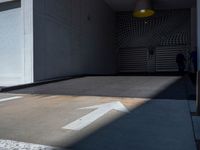 a shadow on a wall with an arrow sign on the ground near a door to a parking garage