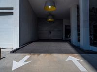 a room with two white arrows painted on it's concrete floors and a yellow light hanging above