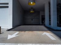 a room with two white arrows painted on it's concrete floors and a yellow light hanging above