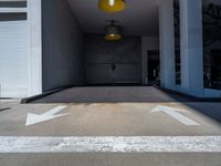 a room with two white arrows painted on it's concrete floors and a yellow light hanging above