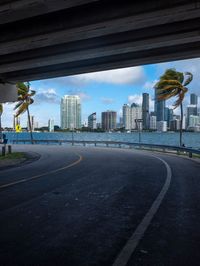 view of downtown miami from beneath highway bridge on a sunny day with palm trees in the distance