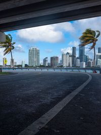 view of downtown miami from beneath highway bridge on a sunny day with palm trees in the distance