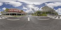 a street lined with empty streets under cloudy skies near tall buildings in front of a shopping center