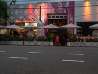 an empty street with tables and umbrellas outside of a restaurant that is set up for diners