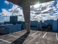 a parking garage with a sky and clouds in the background taken from inside a building