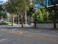 a city street with a sign on the corner of the road in front of trees