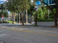 a city street with a sign on the corner of the road in front of trees