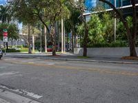 a city street with a sign on the corner of the road in front of trees