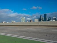 a street view with the city skyline in the distance with clouds overhead on a sunny day