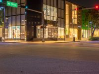 traffic lights sitting on the corner of a street at night time in front of a building