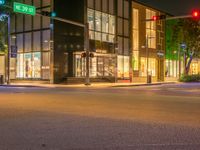 traffic lights sitting on the corner of a street at night time in front of a building