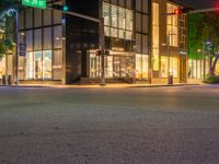 traffic lights sitting on the corner of a street at night time in front of a building