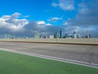 a highway sign and building against a blue sky and white clouds in miami florida with the city skyline seen behind