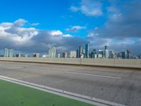 a highway sign and building against a blue sky and white clouds in miami florida with the city skyline seen behind