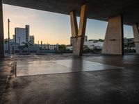 a skateboarder performing tricks in an empty concrete lot with tall buildings in the background