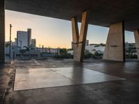 a skateboarder performing tricks in an empty concrete lot with tall buildings in the background