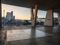 a skateboarder performing tricks in an empty concrete lot with tall buildings in the background