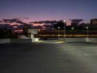 an empty parking lot with a light at the end of it and street lights in the distance