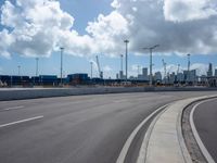 this is an empty highway in an urban setting in the background of city buildings and clouds