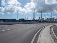 this is an empty highway in an urban setting in the background of city buildings and clouds