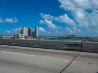 an empty freeway with two lane street alongside the large city skyline in the distance while blue sky and clouds above