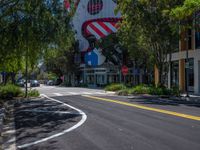 this is a street with trees and buildings on both sides of the road in the daytime sun