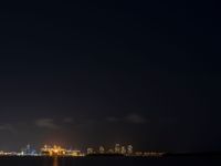 night scene with a view of the city lights and river from across the bay, and city skyline in distance