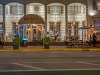 the entrance to the restaurant is lit up by candles and umbrellas on the sidewalk