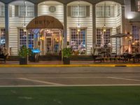 the entrance to the restaurant is lit up by candles and umbrellas on the sidewalk