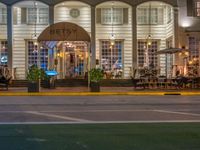 the entrance to the restaurant is lit up by candles and umbrellas on the sidewalk