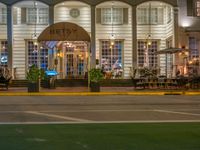 the entrance to the restaurant is lit up by candles and umbrellas on the sidewalk