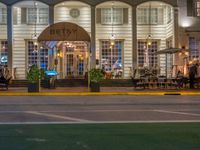 the entrance to the restaurant is lit up by candles and umbrellas on the sidewalk