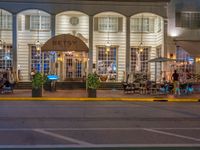 the entrance to the restaurant is lit up by candles and umbrellas on the sidewalk