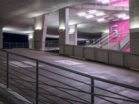 a stairway leading up to a building with stairs on each side of it and pink lights in the ceiling