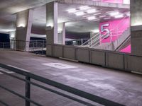 a stairway leading up to a building with stairs on each side of it and pink lights in the ceiling