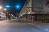 there is a stop light on the street corner by the store fronts at night in this picture