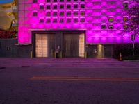 the purple lights are shining on an empty parking lot near a building with a garage