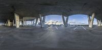 a fish eye lens view of an empty concrete building with city in the background and a few columns